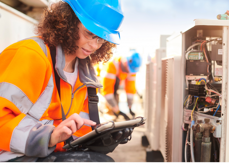 Female in construction attire holding a clipboard at a worksite 