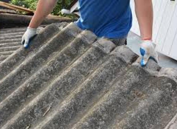 person lifting a corrugated asbestos sheet 