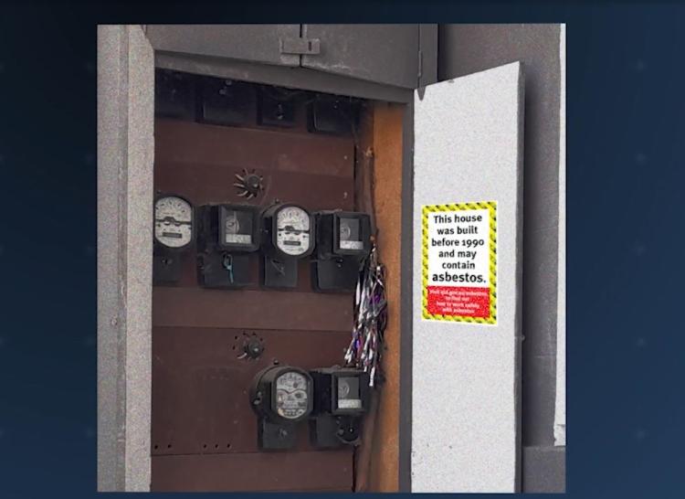 Electrical board with an asbestos warning sticker on the inside door
